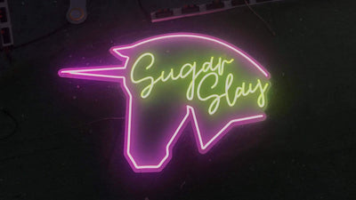 Neon sign of a unicorn with 'Sugar Slays' text on a dark background