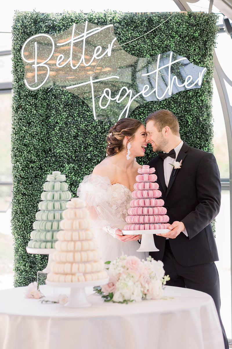 Wedding couple with colorful macaron towers against a greenery backdrop with 'Better Together' text.