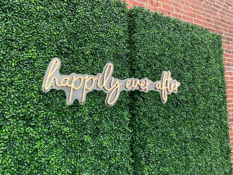 Decorative sign with 'happily ever after' on a green wall.