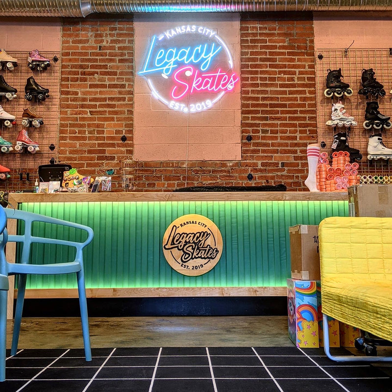 Neon sign and counter with 'Legacy Skates' branding in a skate shop setting.