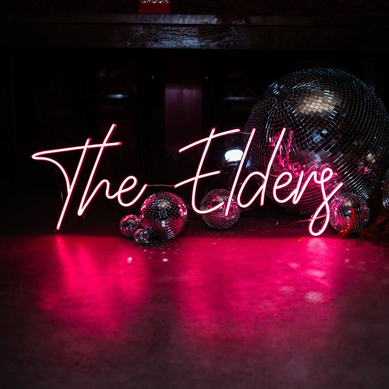 Neon sign reading 'The Elders' with disco balls on a dark background