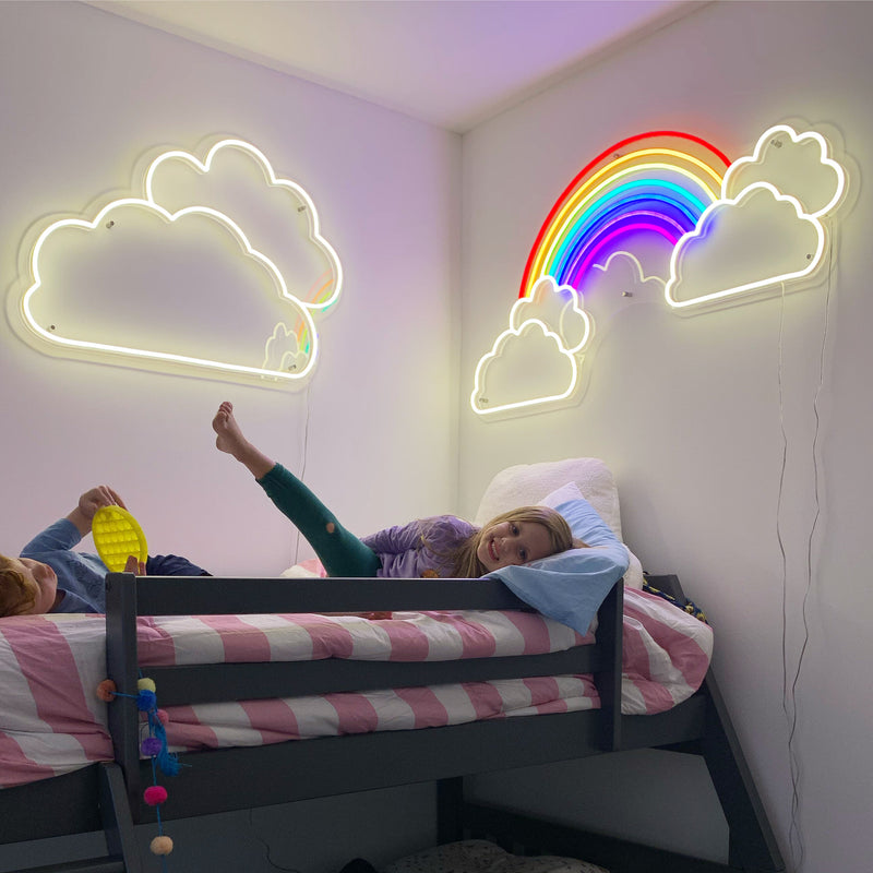 Children in a bedroom with neon cloud and rainbow lights on the wall.