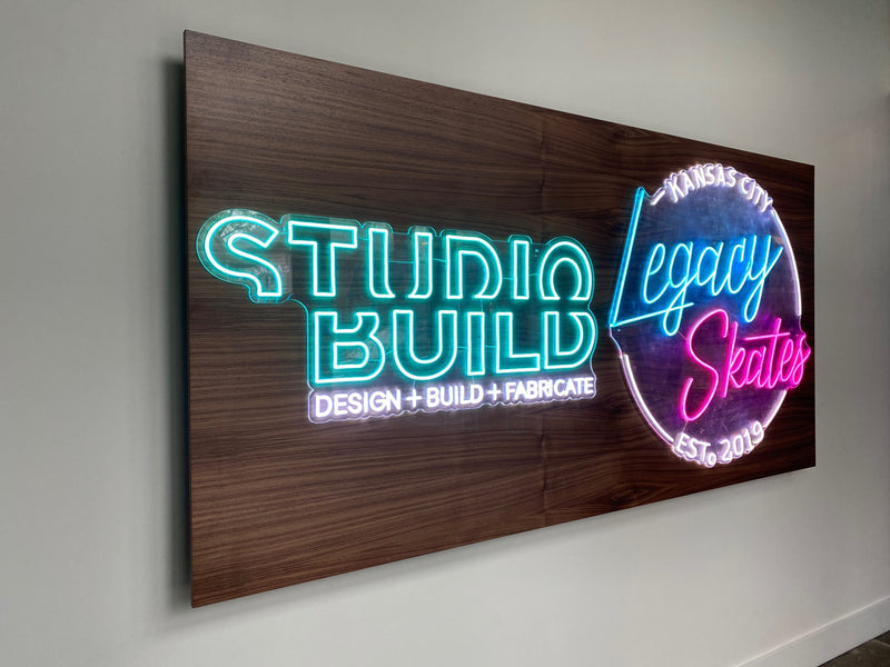 Neon sign on a wooden panel with 'Studio Build' and 'Legacy Skates' branding.