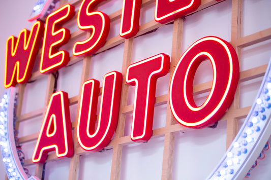 Neon sign with 'WEST AUTO' on a wooden background